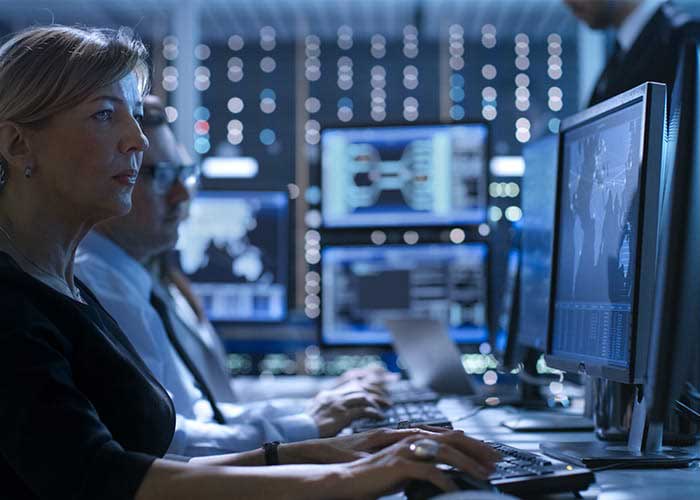 A woman looking at a computer screen in a control room.
